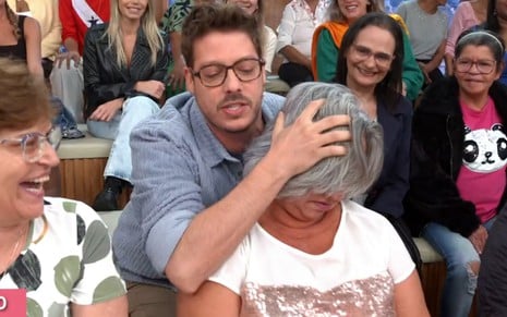 Fabio Porchat segurando uma mulher da plateia do Encontro pela cabeça
