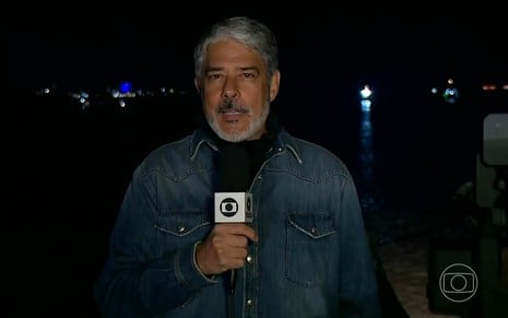 William Bonner durante o Jornal Nacional de quinta-feira, diretamente de navio da Marinha, em Porto Alegre; ele usa camiseta preta e camisa jean