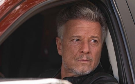 O ator Marcello Novaes está dentro de um carro, com expressão séria, na série Justiça 2 como Egisto