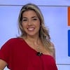 A apresentadora Silvana Freire posa no cenário do telejornal Bom Dia Bahia, da TV Aratu; ela está com blusa vermelha e saia florida