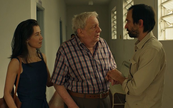 Carolina (Marjorie Estiano), Heleno (Marco Nanini) e Evandro (Julio Andrade) caminham lado a lado em cena de Sob Pressão